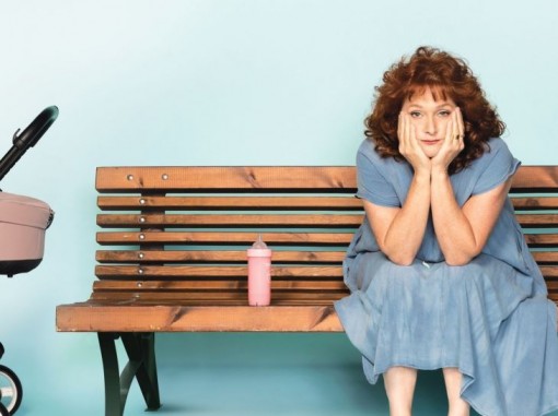 שחקנית אודיה קורן יושבת על ספסל אוחזת בראשה