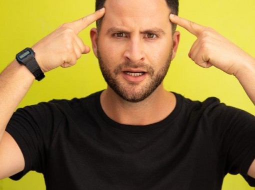 דיוקן גיא הוכמן מצביע באצבעותיו על מצחו