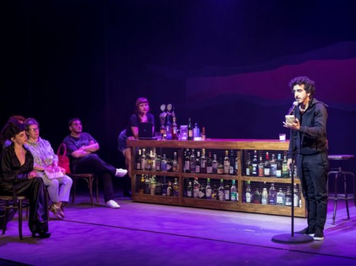 בחור מדבר למיקרופון וקהל ליד בר משקאות