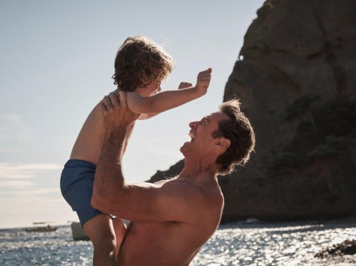 אב מניף באוויר את בנו על חוף הים