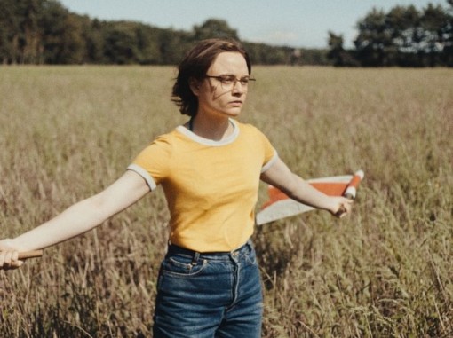 צעירה מחזיקה דגל ברוח נוף כפרי