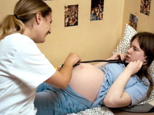 אימא הריונית מאזינה בסטטוסקופ לבטנה