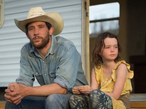 צעיר בכובע בוקרים וילדה קטנה יושבים בפתח קרוון