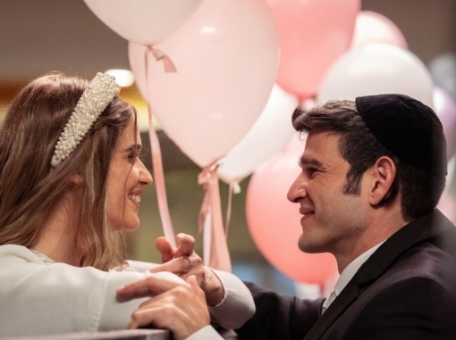 תקריב חתן וכלה מחויכים ברקע בלונים